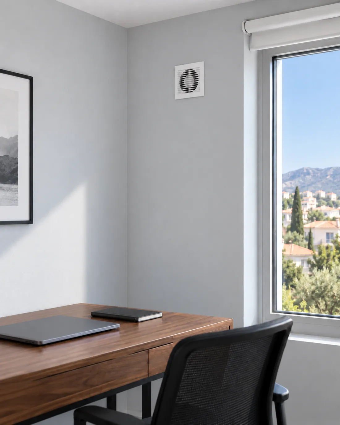 The indoor grille of a recuperator above a desk in a home office.